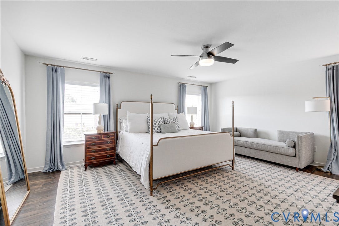 1733 W Cary Street, Richmond, VA 23220 Spacious primary bedroom with ceiling fan with integrated light, wood-finish flooring, multiple windows, and neutral wall tones
