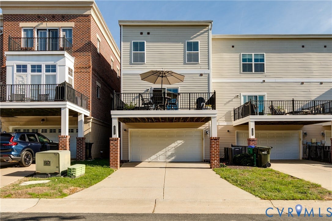 1733 W Cary Street, Richmond, VA 23220 Multi-level townhome featuring a two-car garage, upper-level balcony, and a paved driveway