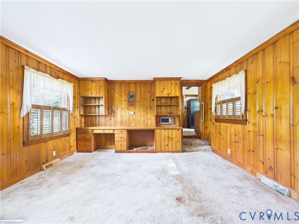 Wood-paneled walls with built-in desk, shelving, and window shutters