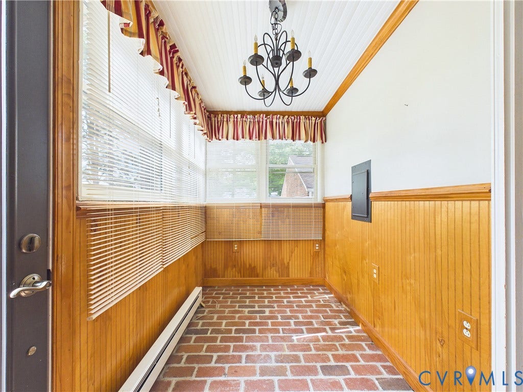 Brick flooring, wood-paneled walls, multiple windows with blinds, beadboard ceiling, and a chandelier fixture