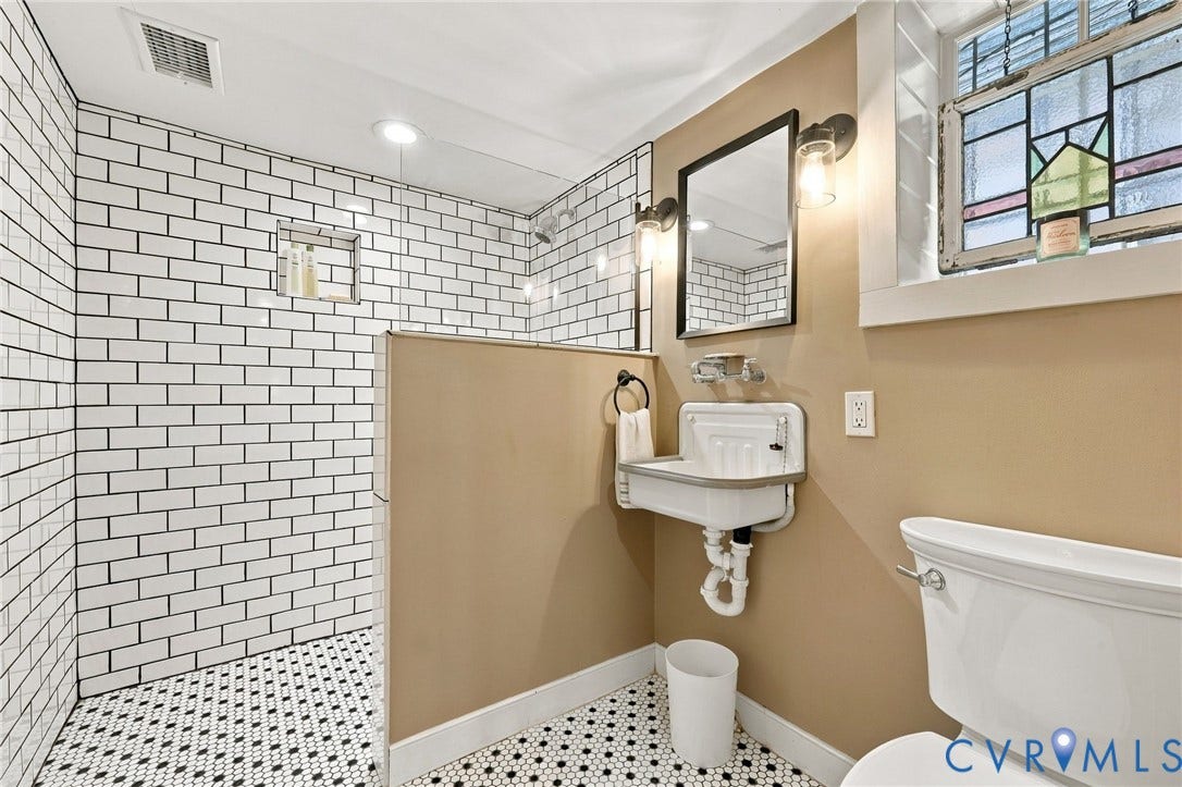 Basement bathroom with white subway tile shower with black hex tile flooring