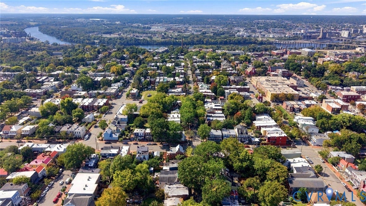 Expansive cityscape with a prominent river, dense tree canopy, and residential areas