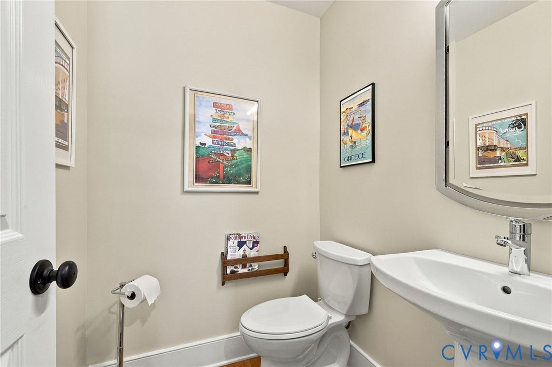 Pedestal sink with chrome faucet, toilet, and a framed mirror