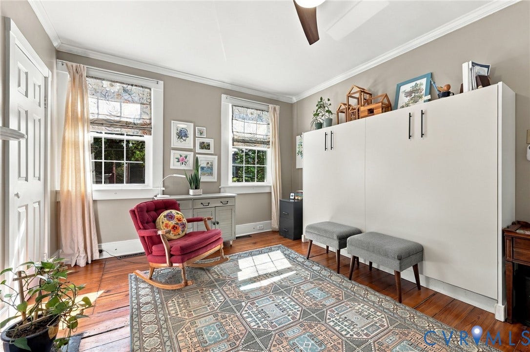 Hardwood flooring, painted walls, crown molding, double windows with window treatments, and a built-in storage unit