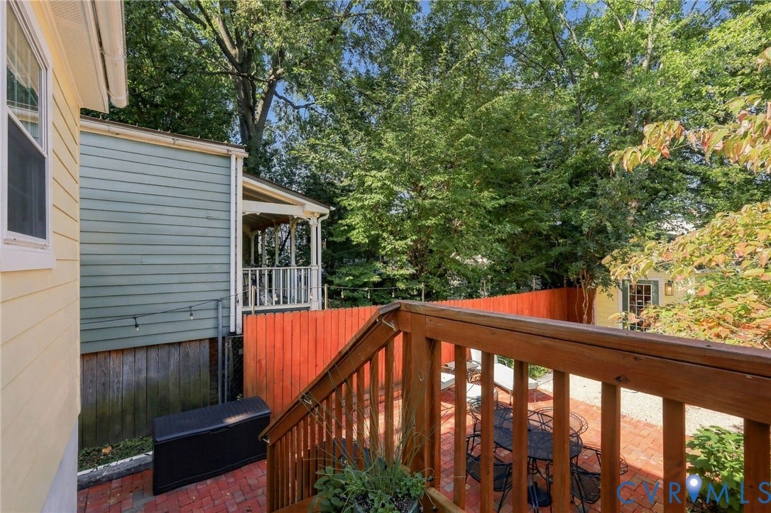 Wood deck with railings overlooking a brick patio