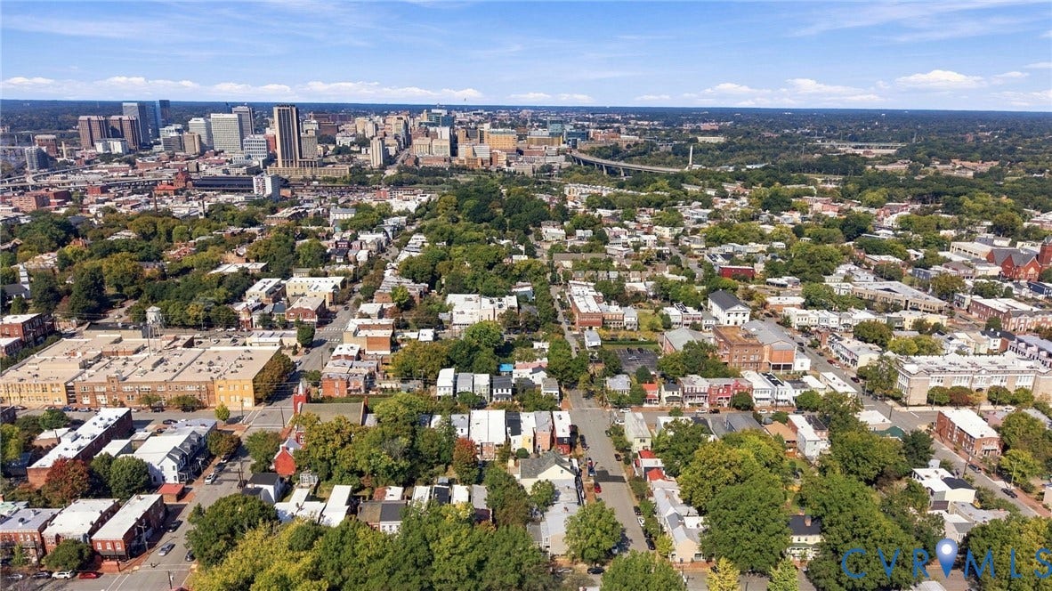 Urban landscape featuring a prominent city skyline, residential areas, and a tree-lined street grid