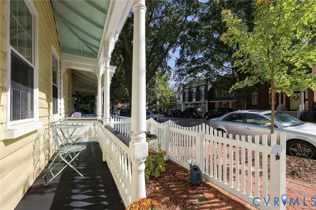 Inviting front porch featuring spindle railings, ornate corbels, and a painted ceiling