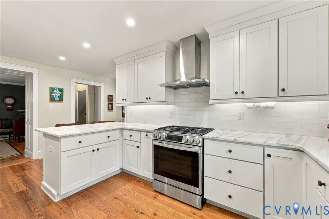 White shaker cabinetry, stone countertops, subway tile backsplash, stainless steel gas range, and wood-finish flooring