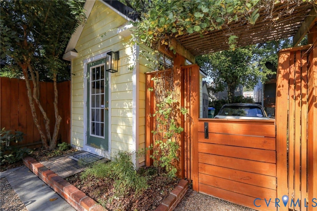 Exterior structure with yellow siding, a full-lite entry door, and an exterior wall lantern