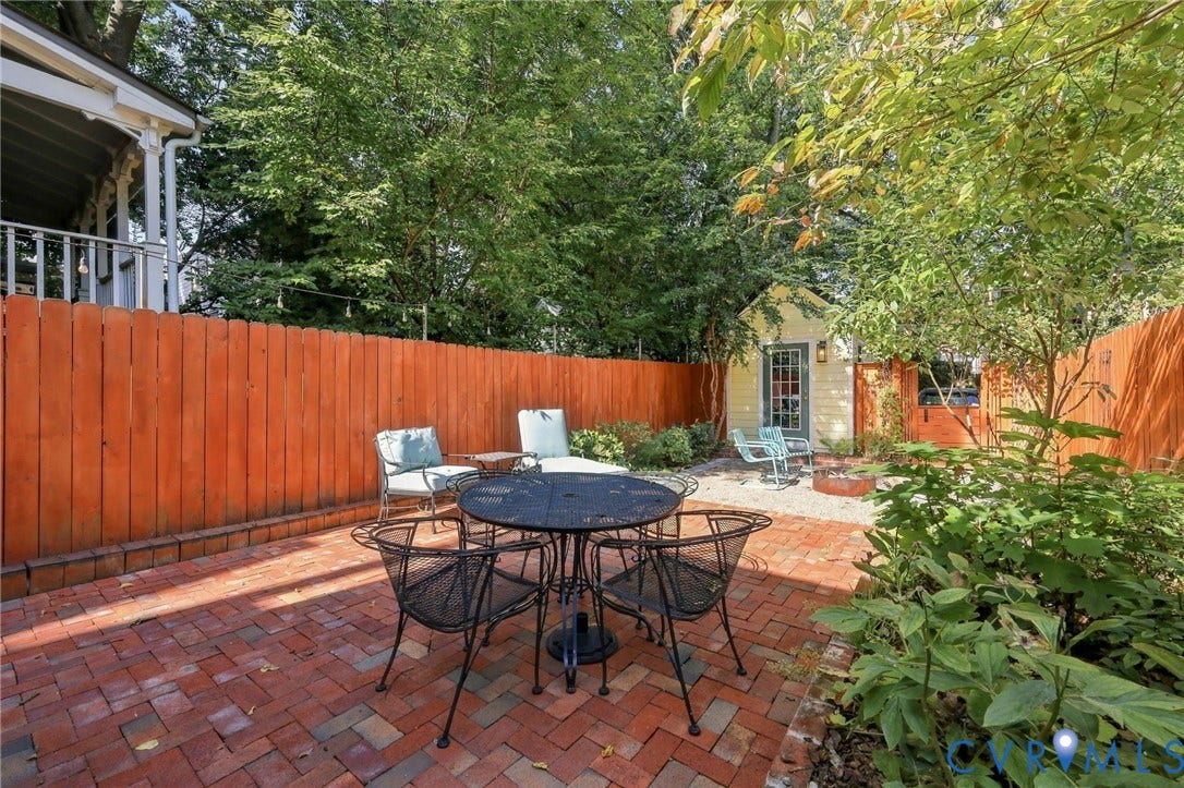 Brick paver patio, wood privacy fence, gravel seating area, exterior building with French door, mature landscaping