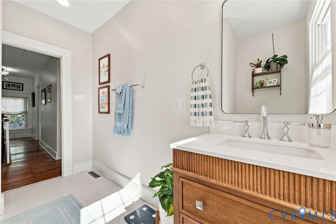 White countertop with an integrated sink, polished chrome faucet, and a wood-finish vanity