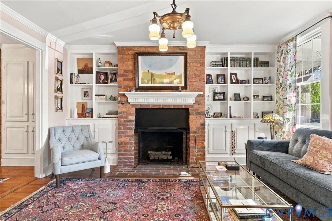 Exposed brick fireplace with a white mantel, flanked by built-in shelving and lower cabinetry