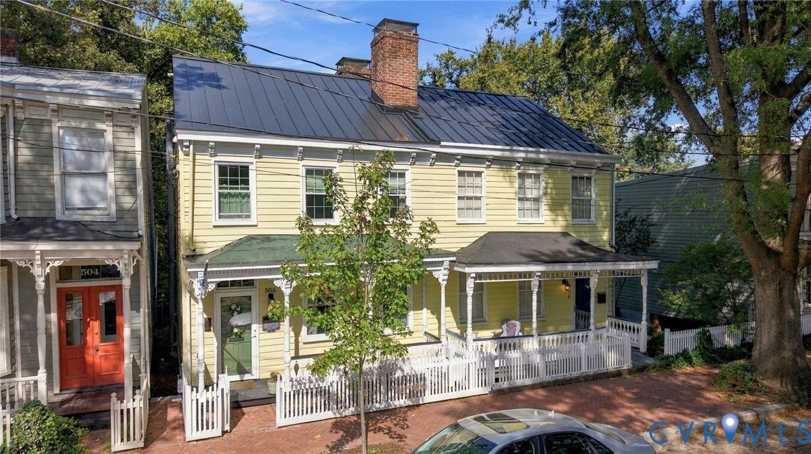 Two-story exterior with light yellow siding and a dark metal roof