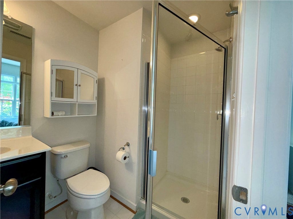 3931 Liesfeld Place, West Broad Village, Henrico, VA 23060 Bathroom featuring a glass-enclosed shower, white tiled shower surround, recessed shower lighting, and a wall-mounted medicine cabinet with mirrored doors