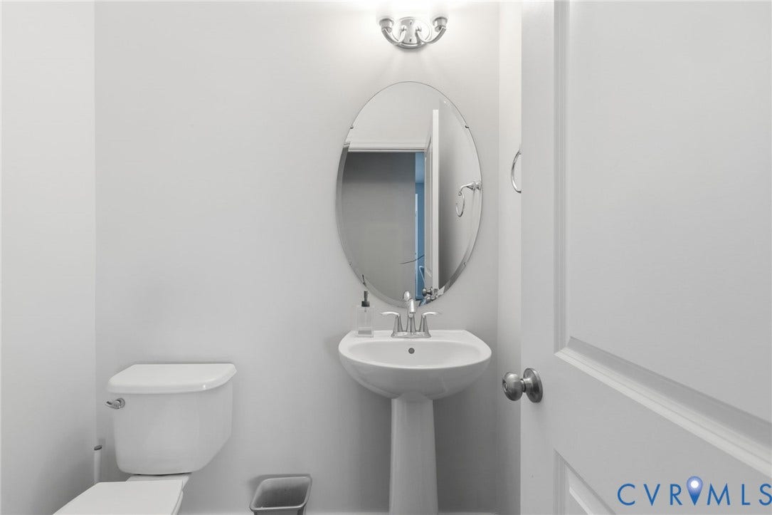 3931 Liesfeld Place, West Broad Village, Henrico, VA 23060 Pedestal sink with chrome-finish faucet, oval mirror, wall-mounted light fixture, and white toilet