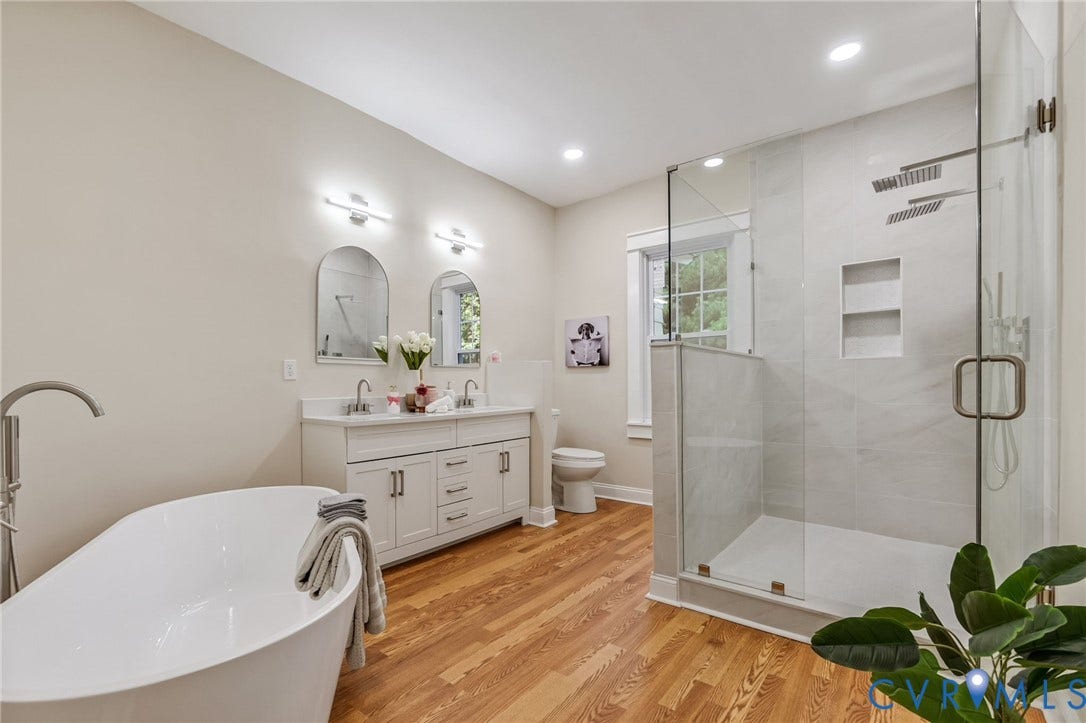 12105 Mathenay Drive, Mathenay, Chesterfield, VA 23831 Freestanding soaking tub with floor-mounted faucet, dual vanity with undermount sinks, separate glass-enclosed shower with dual showerheads, and wood-finish flooring
