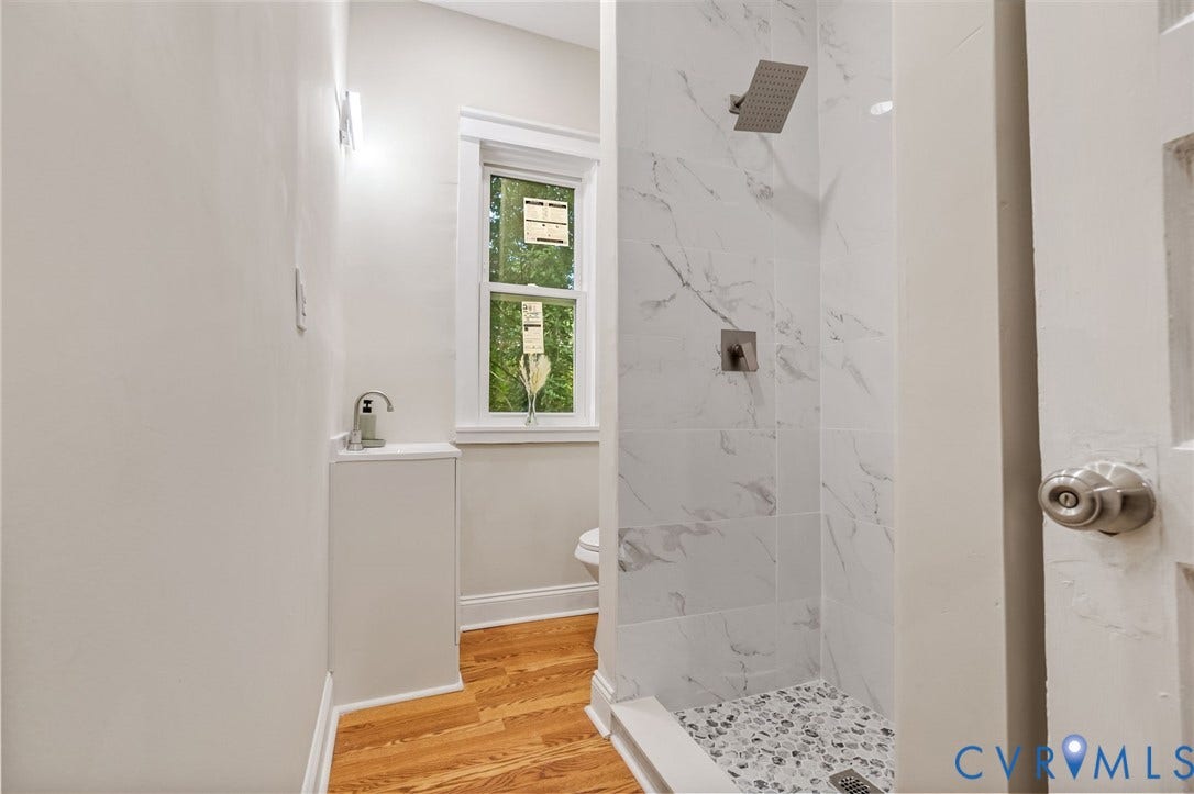 12105 Mathenay Drive, Mathenay, Chesterfield, VA 23831 Walk-in shower with rain showerhead, white marble-look wall tiling, pebble-finish shower floor, and wood-finish flooring