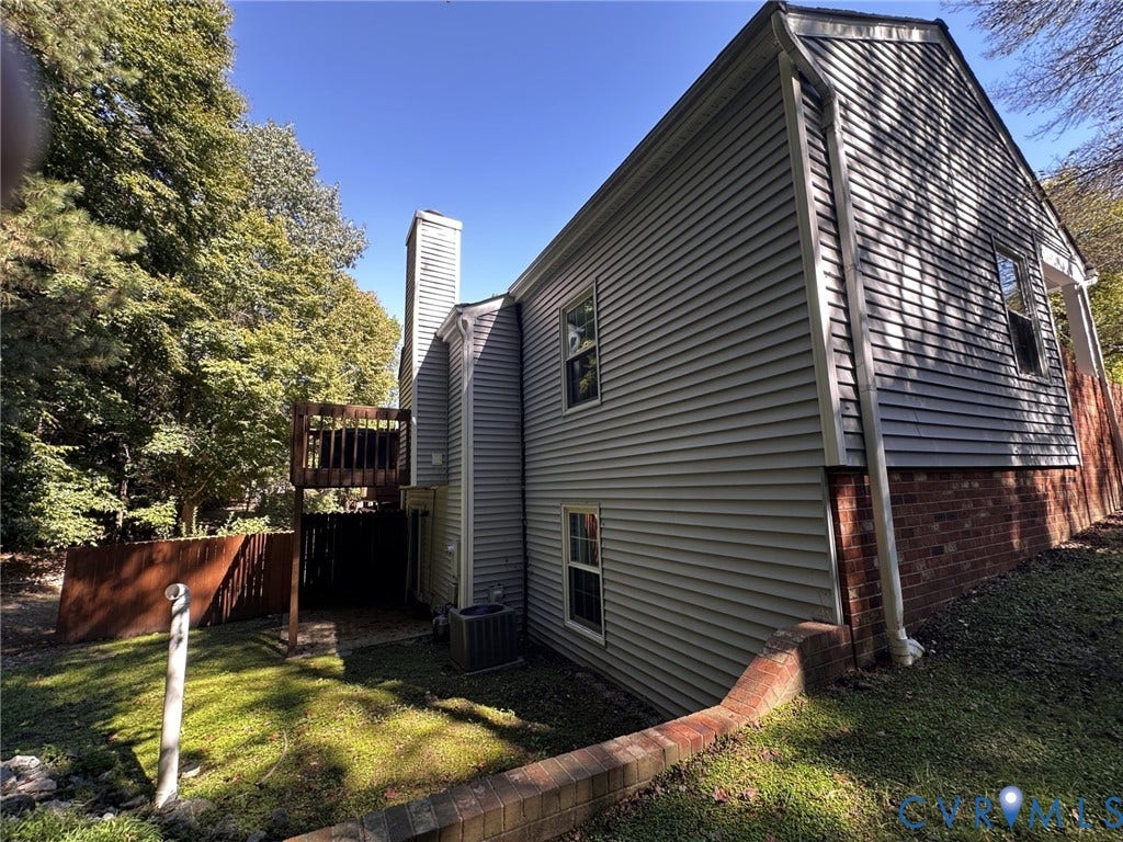 Multi-level exterior with light gray siding, brick foundation, and a prominent chimney