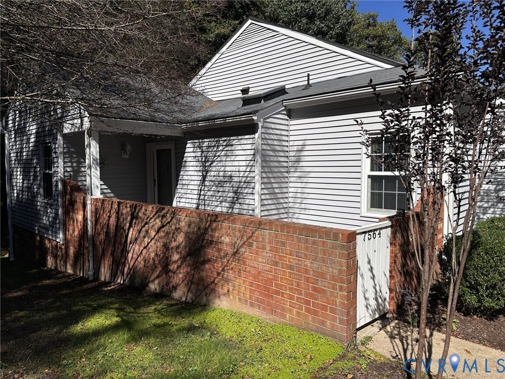 Exterior featuring horizontal siding, a covered porch entry, a brick privacy wall, a front window with grilles, and a shingled roof