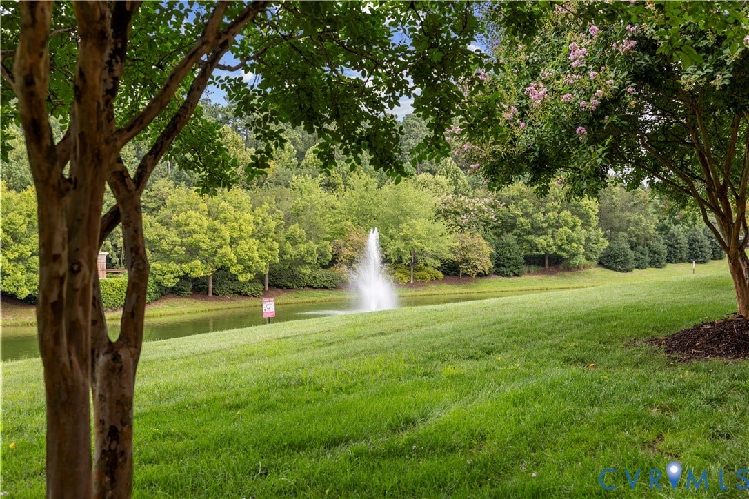 Expansive green space featuring a serene pond with a central fountain, mature trees, and a tree-lined perimeter