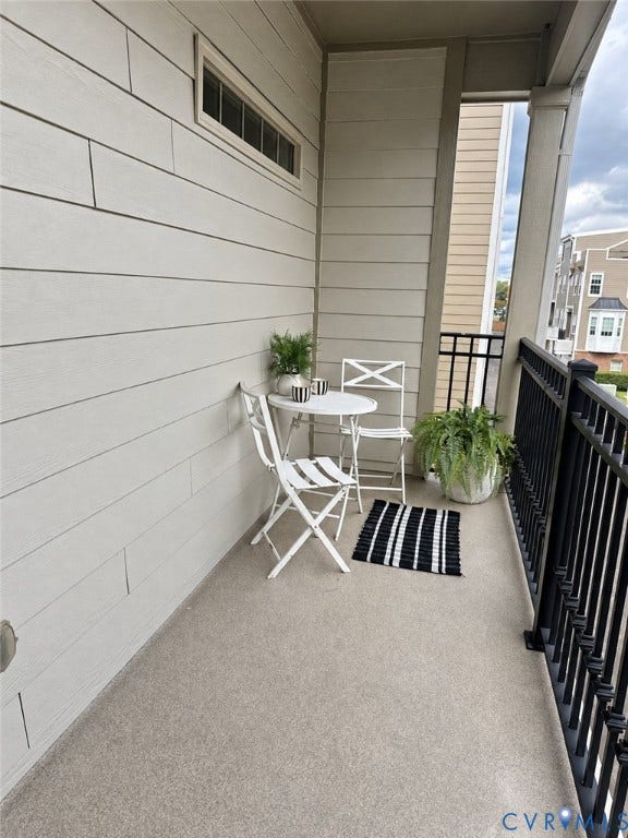 Private balcony featuring durable exterior siding, a secure black metal railing, and a textured concrete floor