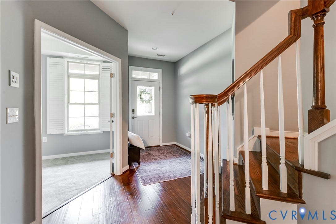 Hardwood flooring, painted interior walls, white paneled doors, white window shutters, and a wooden staircase