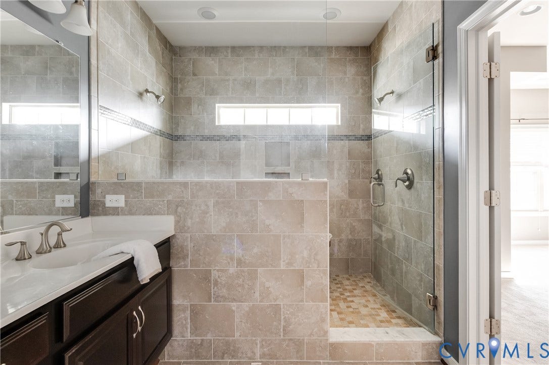 Walk-in shower with clear glass enclosure, tiled walls, and a recessed shampoo niche
