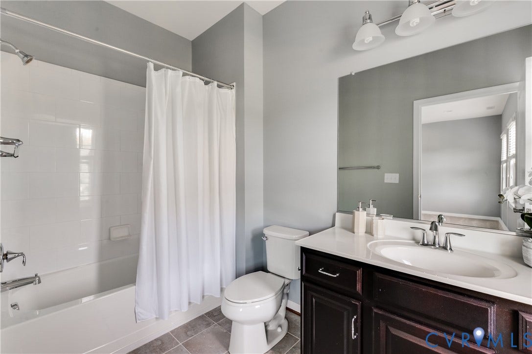 Vanity with a white countertop and undermount sink, dark wood-finish cabinetry, a large mirror, and overhead lighting