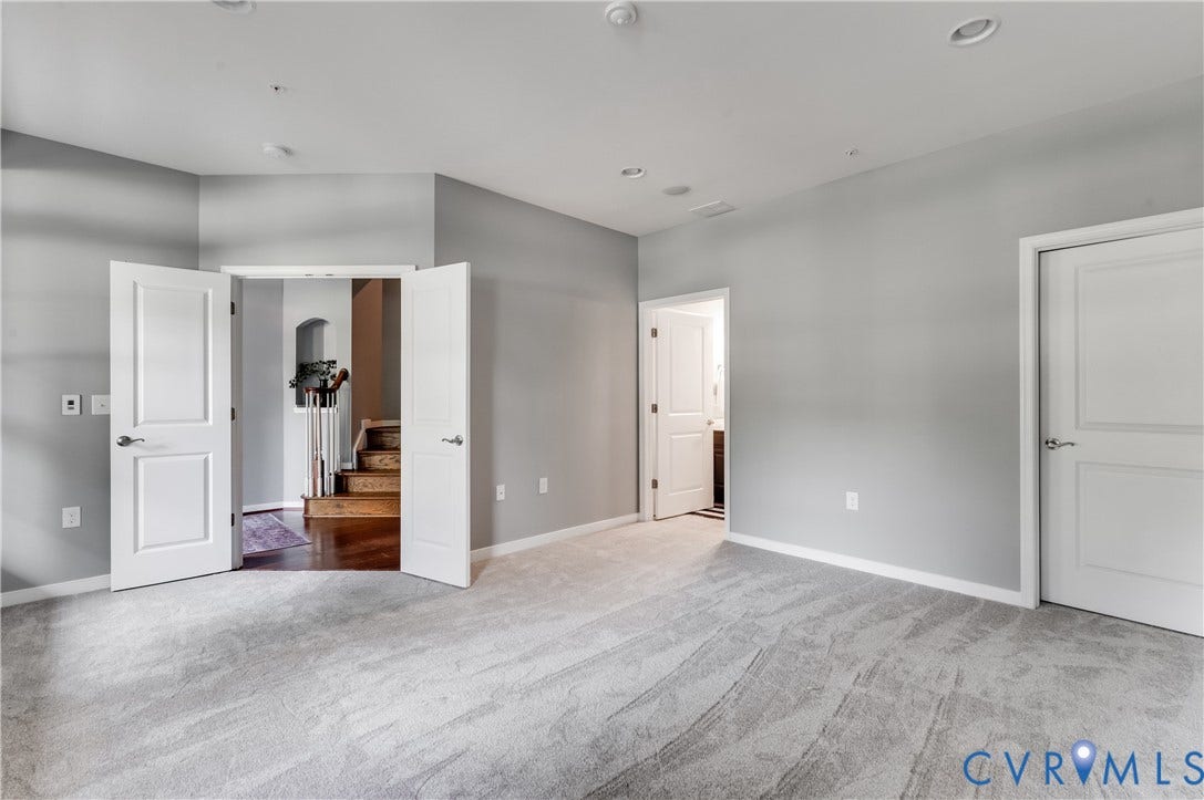 Recessed lighting, light gray wall finishes, light gray carpeting, white interior doors, and a wood-finish staircase