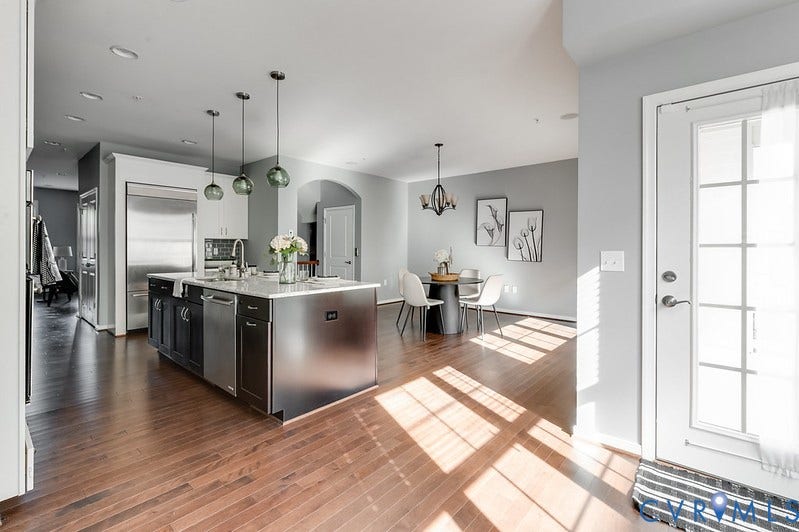 Wood-finish flooring, central kitchen island with countertop, stainless steel appliances, recessed lighting, and pendant lighting fixtures