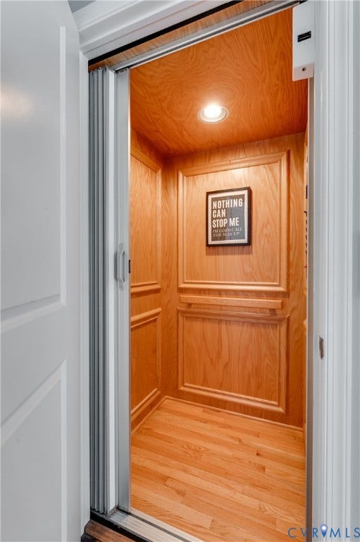 Wood-paneled interior elevator featuring recessed lighting and a wood-finish floor