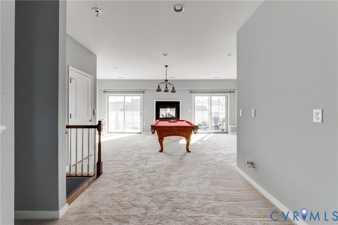 Carpeted room with a fireplace, recessed lighting, and dual sliding glass doors