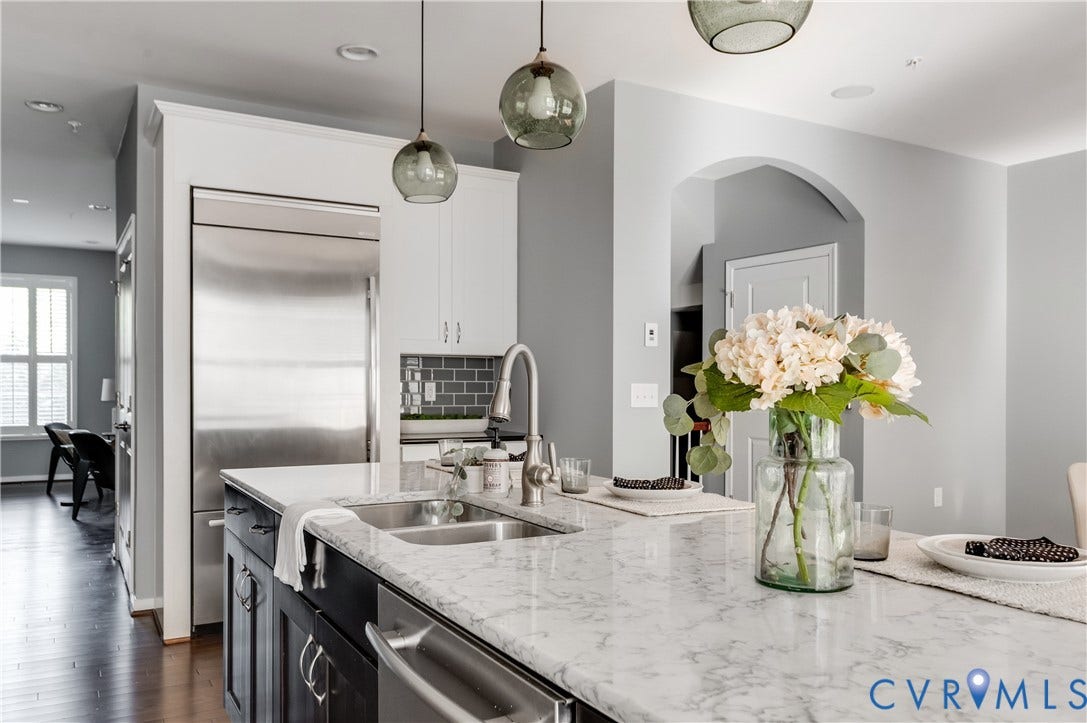 Kitchen island with a double basin sink, stainless steel faucet, and light-toned countertop