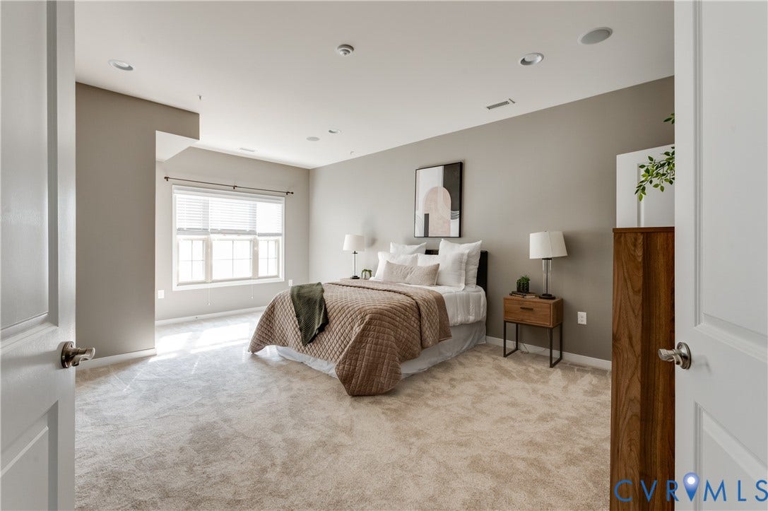 Spacious room featuring neutral carpeting, a large window with blinds, recessed lighting, and light gray wall paint