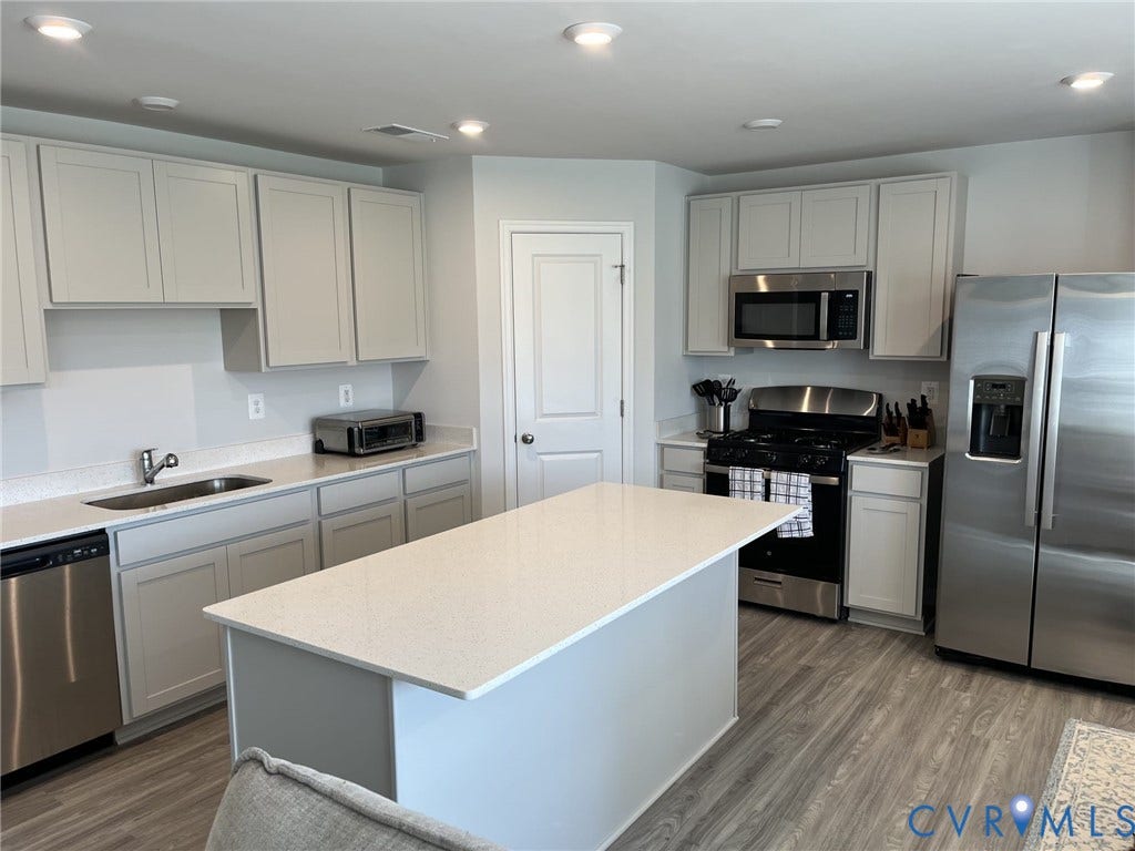 321 Camerons Ferry Drive, Glen Allen, VA 23060 Kitchen featuring light-toned cabinetry, light-toned countertops, stainless steel appliances, a central island, and wood-finish flooring