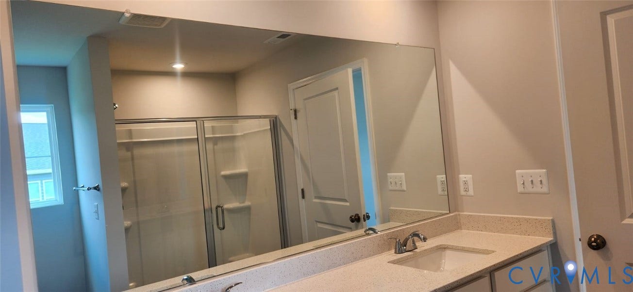 321 Camerons Ferry Drive, Glen Allen, VA 23060 Elongated vanity mirror, single basin sink, chrome faucet, white cabinetry, and shower with sliding glass enclosure