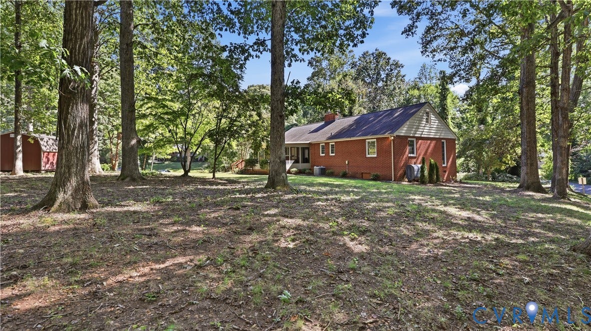 Expansive rear yard featuring mature trees and a detached shed