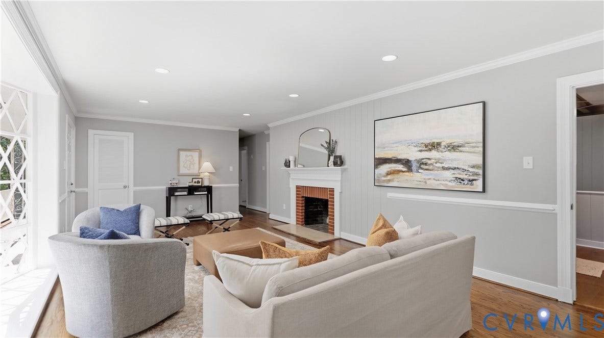 Hardwood flooring, recessed lighting, white crown molding, brick fireplace with white mantel, and white paneling