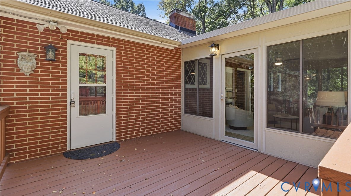 Expansive outdoor deck with brick exterior, multiple entry points, and a sunroom with ample natural light