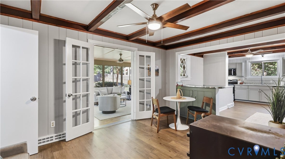 Wood-finish flooring, exposed ceiling beams, white ceiling fans, and a kitchen with light gray cabinetry and a gray countertop