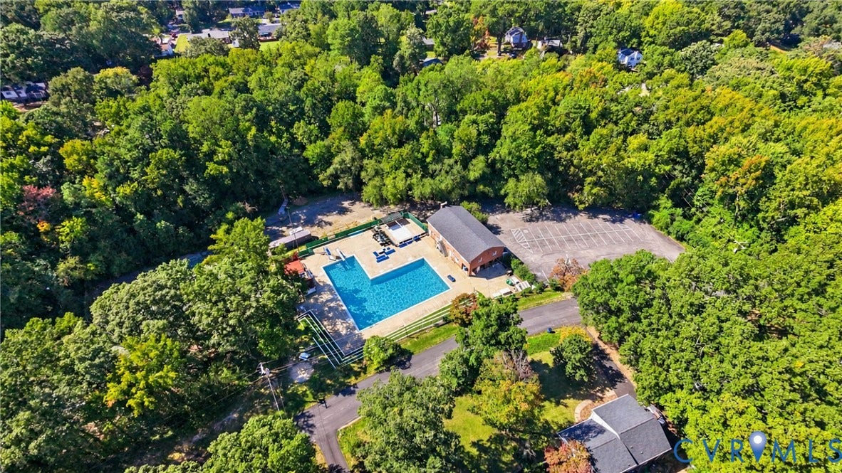 Expansive property featuring a large swimming pool, surrounding green space, and a dedicated parking area