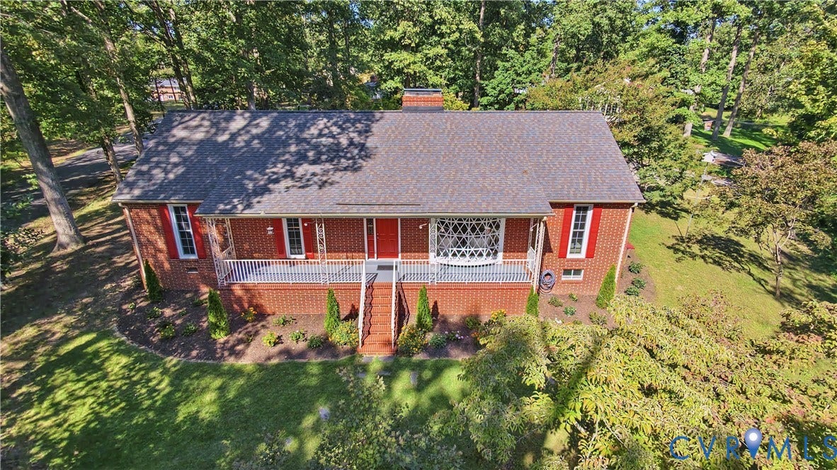 Brick exterior with covered porch, decorative railings, and a peaked roof
