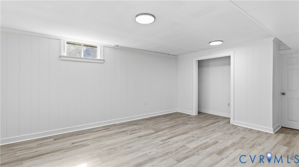 Recessed ceiling lighting, wood-finish flooring, white panel walls, and a window