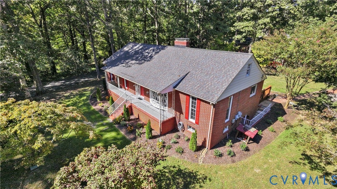 Brick exterior with a gray shingle roof, complemented by a covered porch with white railings