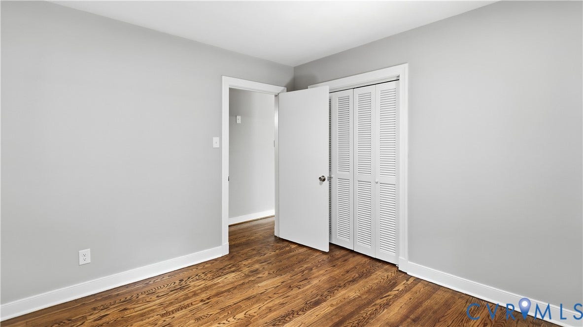 Wood-finish flooring, white baseboards, and a louvered bi-fold closet door