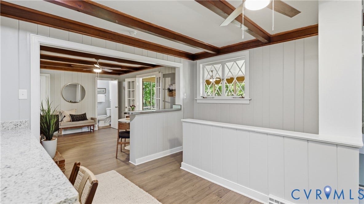 Wood-finish flooring throughout, exposed ceiling beams, white paneling, and a transom window