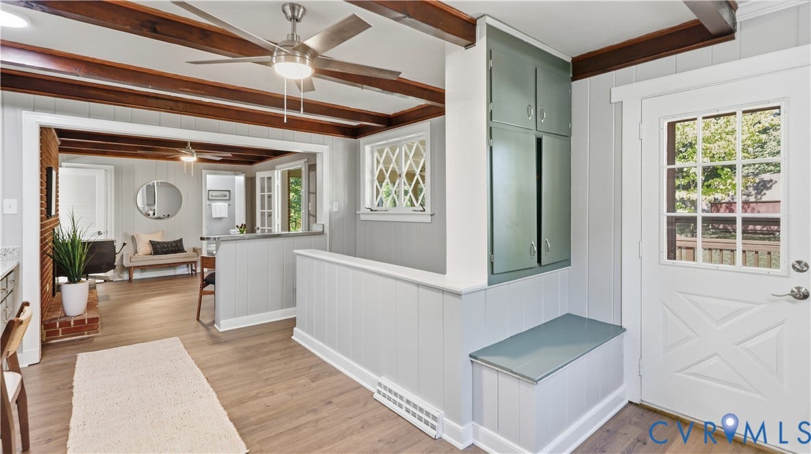 Exposed wood beam ceiling, wood-finish flooring, built-in cabinetry, picture window with diamond muntins, and a glass-paned door