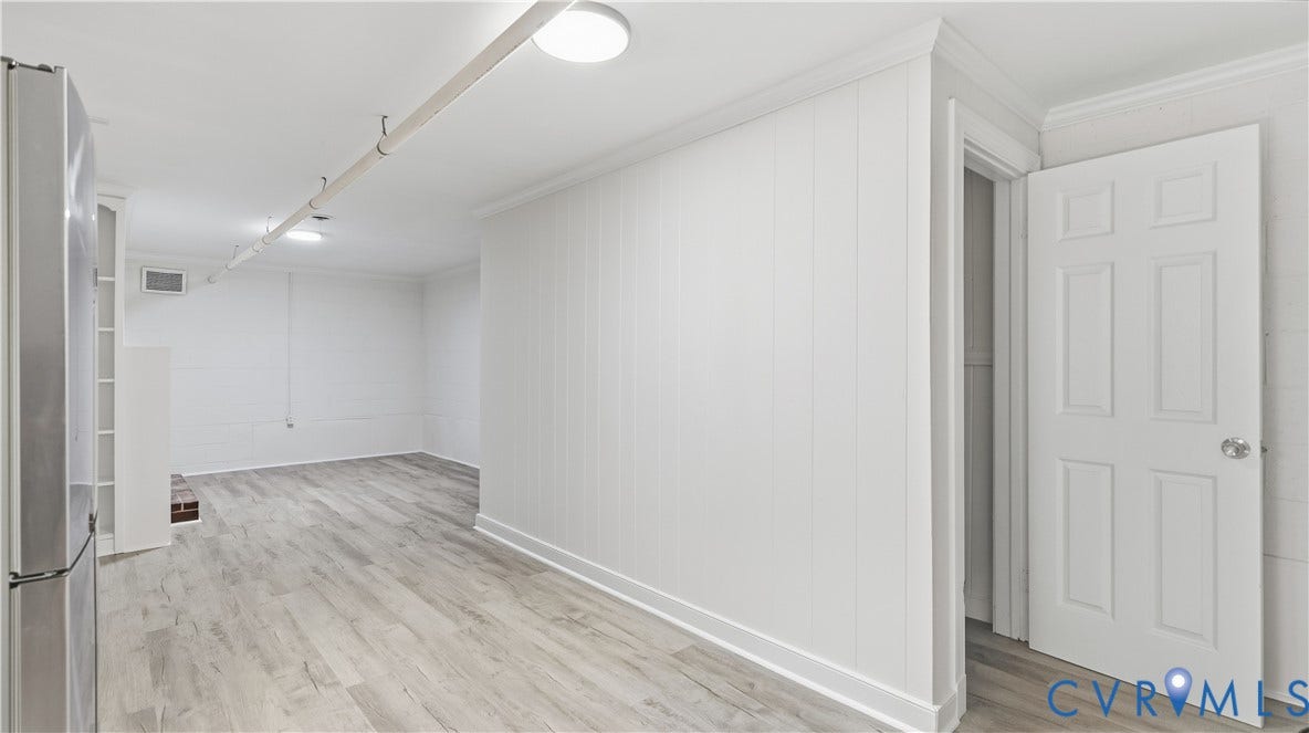 Recessed lighting fixtures, wood-finish flooring, white paneling, and an interior six-panel door