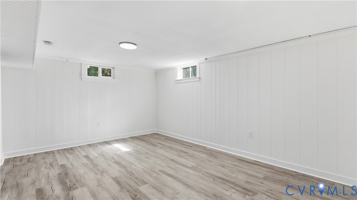 Paneling walls, wood-finish flooring, two rectangular windows, flush-mount ceiling light