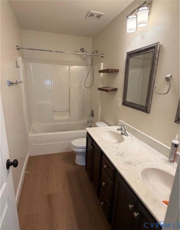 7319 Vicenzo Drive, Moseley, VA 23120 Dual vanity with integrated sinks and countertop, dark wood-finish cabinetry, wood-finish flooring, and a shower-over-tub combination